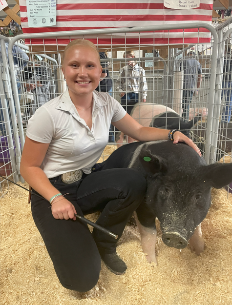 Rylee Snodgrass sits with her market hog, Goose at the Chelan County Fair.