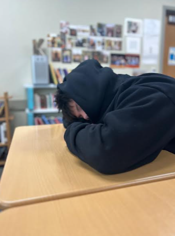 Sophomore Alvaro Ferrer-Sierra rests his head on his desk as a tiring and chaotic school day rages on around him. He woke up at 5:45 and could barely make it through the day.
