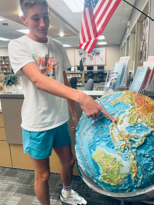 Oscar Green, a sophomore at Cashmere High School, points towards Singapore on the library globe, a country that he once called home. 
