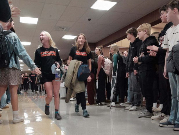Runners Maggie Butcher and Allie Neff walk down the hallway during the cross country send-off.
