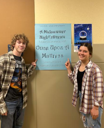 Leads Trip Martin (left) and Eliana Thomas (right) smile and point at a poster hanging in the hallway displaying the performance dates of CHS’s winter musical, Once Upon A Mattress.    